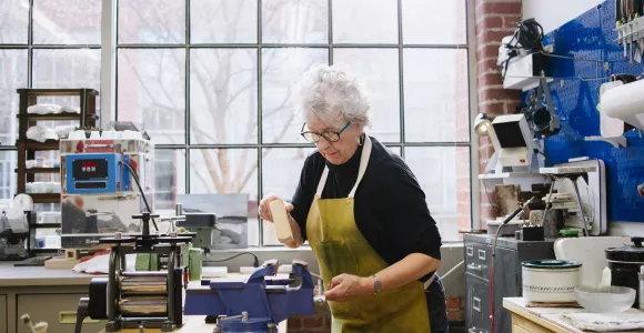une dame âgée travaille le bois dans un menuiserie