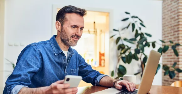 Un homme consulte son ordinateur et sourit