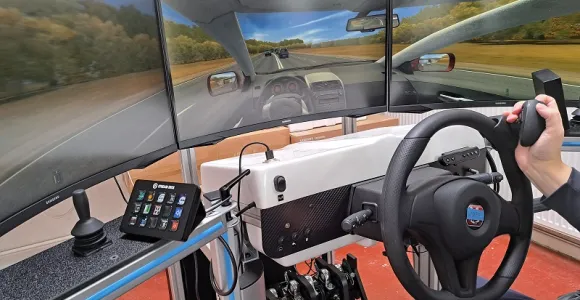Un simulateur de conduite avec un grand écran montrant une route.