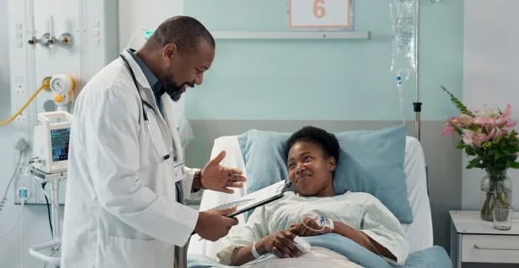 Un médecin donne des informations à une patiente allongée. Les deux personnes sourient. 