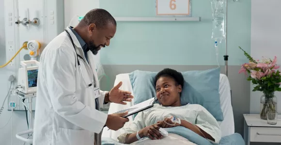 Un médecin donne des informations à une patiente allongée. Les deux personnes sourient. 