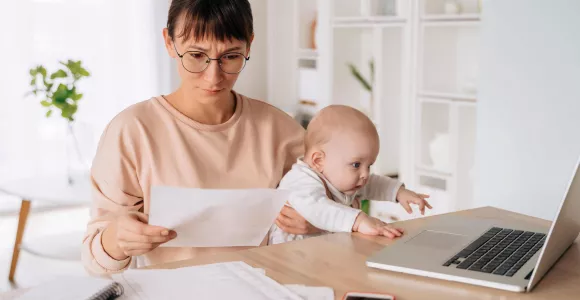 Une maman avec son bébé sur les genoux regarde un dossier