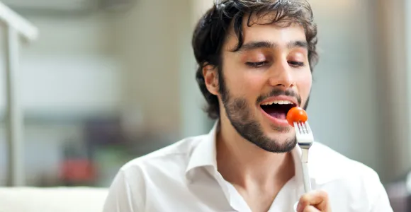 un jeune homme mange une salade