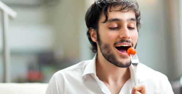 un jeune homme mange une salade