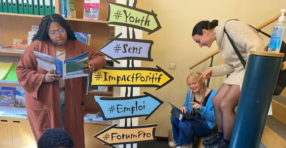 Des jeunes entourent des paneaux de direction qui illustrent les questions d'orientation aux études