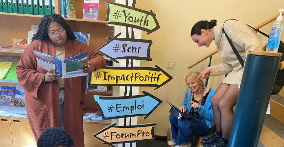 Des jeunes entourent des paneaux de direction qui illustrent les questions d'orientation aux études