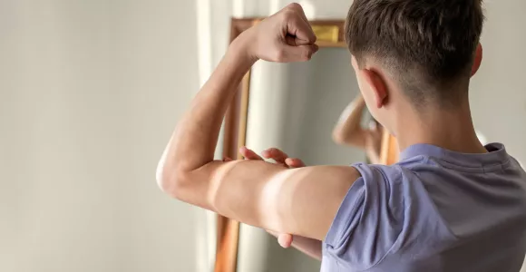 un jeune garçon montre ses muscles devant un miroir