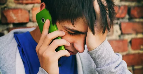 Un jeune homme appelle quelqu'un avec son téléphone.