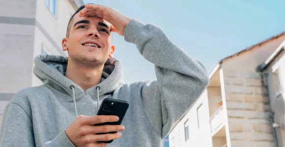 Un jeune sur son GSM regarde en l'air