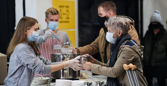 des gens masqués distribuent de la soupe