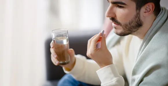 un homme avale un médicament