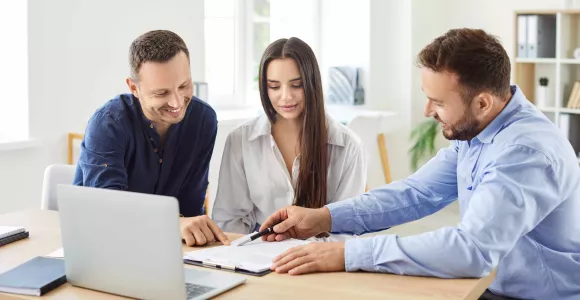 Deux hommes et une femme consultent des informations sur un ordinateur
