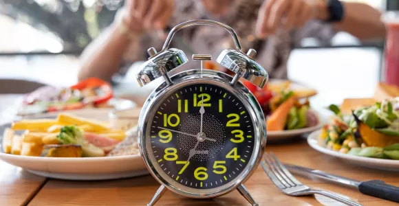 un réveil devant une personne prenant son repas