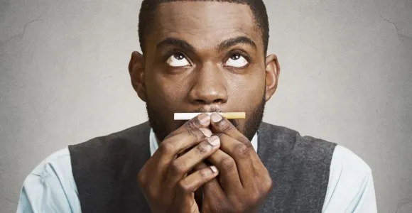 un homme se retient de fumer une cigarette