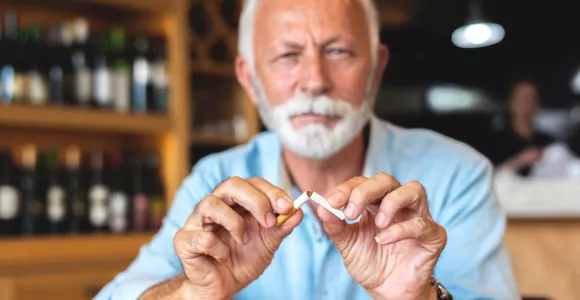un monsieur brise une cigarette en deux
