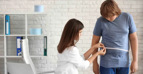 Une médecin mesure le tour de taille d'un adolescent