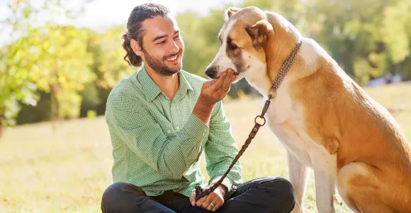 Un homme assis en tailleur caresse son chien assis en face de lui