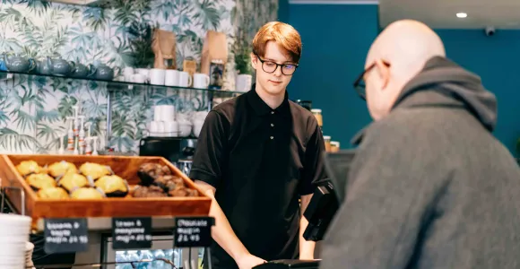 Un étudiant vend du pain à un client dans une boulangerie