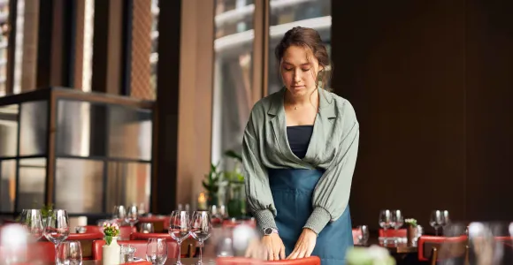 Une étudiante dresse une table de restaurant