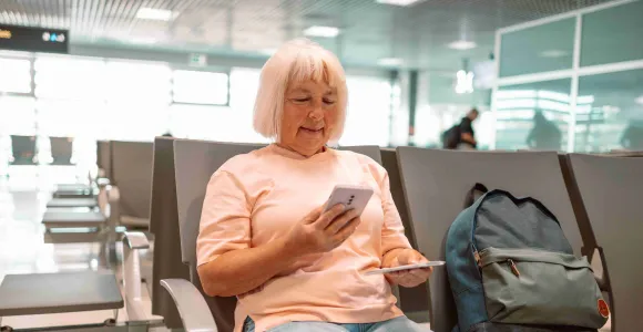 Une dame assise dans un aéroport regarde son passeport