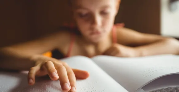 une enfant lit un livre en braille