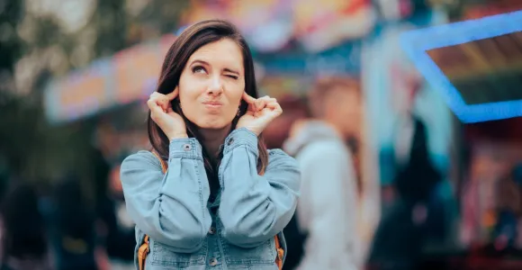 Une femme se bouche les oreilles car elle est dérangée par le bruit