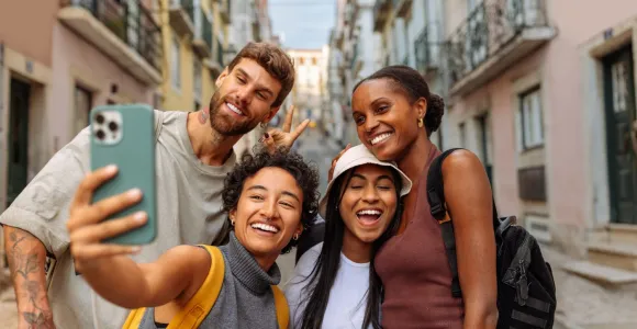 4 jeunes touristes font une photo avec leur téléphone