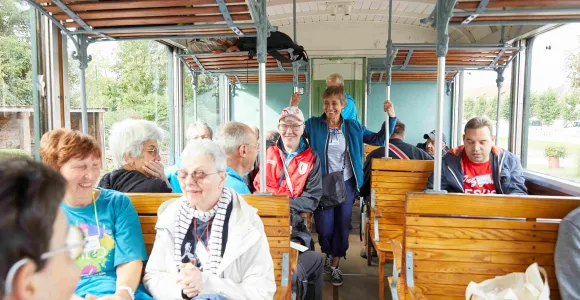 Un volontaire d'Altéo est debout dans un bus rempli de participants souriants