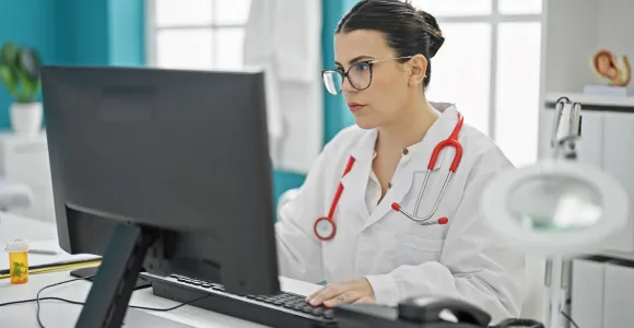une femme médecin encode l'attestation de soins sur son ordinateur