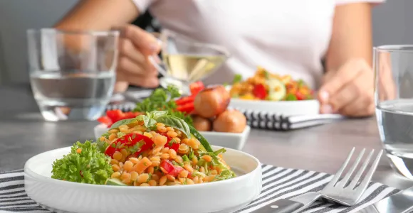 une femme verse de l'huile sur une salade avec pois chiches