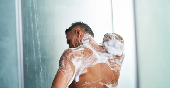 Un homme, de dos, se lave sous la douche