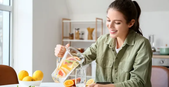 Une femme boit de l'eau aromatisée avec des quartiers d'orange