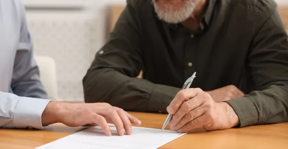 Un homme âgé signe un document pour organiser sa succession