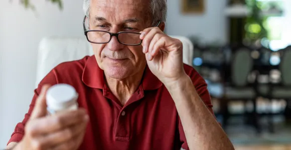 un homme regarde une boite de médicaments