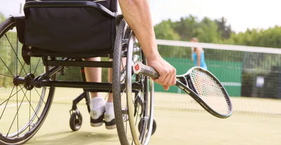 une personne en chaise roulante joue au tennis