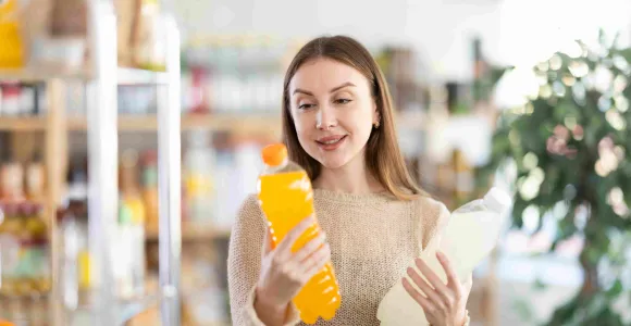 Une femme comprare deux bouteilles de sodas dans un magasin