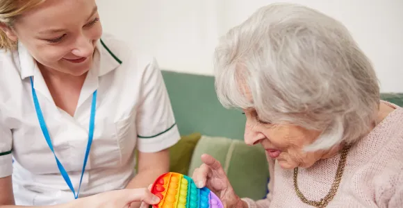 Une infirmière à domicile présente un jeu à une vieille dame