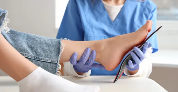 une technologue orthopédique plaque une semelle sur la voûte plantaire d'un patient