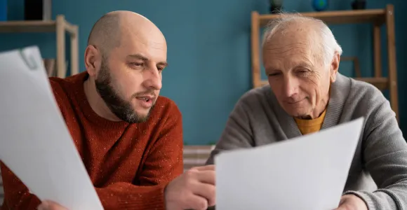 Deux hommes assis à une table comparent des documents