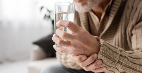 un homme tient un verre d'eau en main