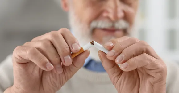 Un homme âgé casse en deux une cigarette