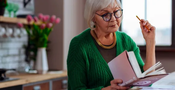 une dame plus agée lit un livre avec intérêt