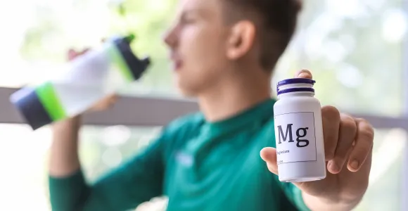 Un sportif tient un récipient de gélule de magnesium