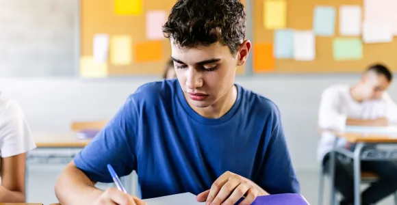 un jeune homme écrit en classe