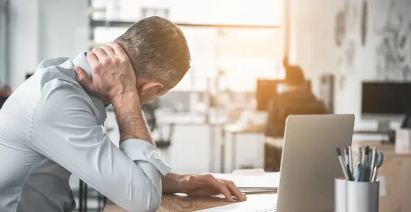 Au bureau, un travailleur qui a mal au dos se tient la nuque 
