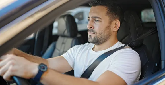Un monsieur au volant de sa voiture