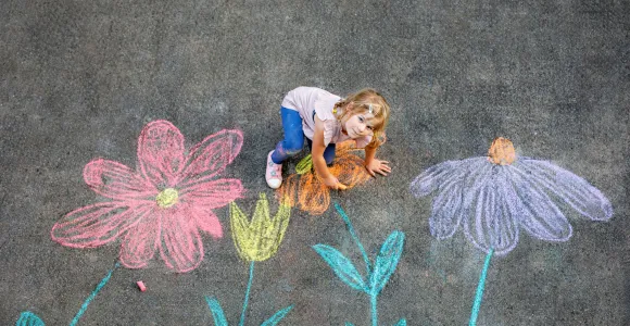 petite fille qui dessine des fleurs sur le béton