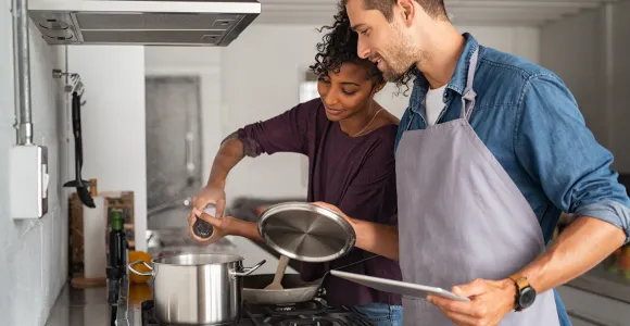 Un couple cuisine et ajoute du sel dans une casserole
