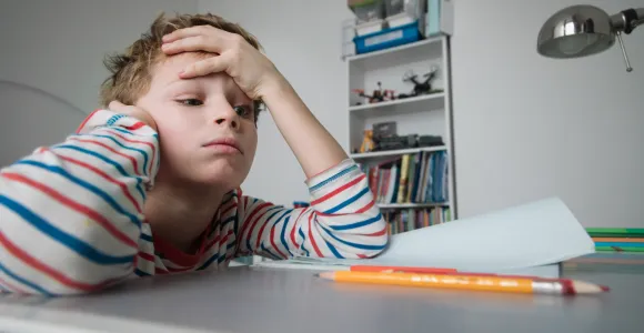 un enfant essaie de se concentrer à sa table de travail
