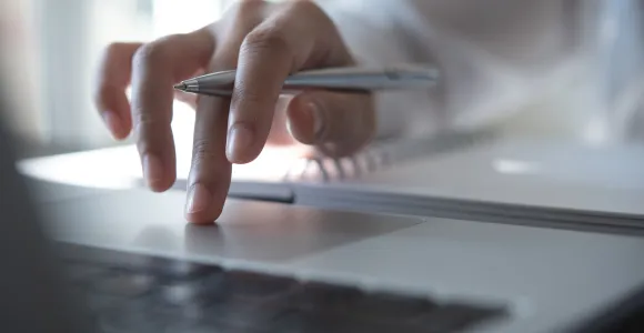gros plan d'une main sur un clavier avec un stylo en main